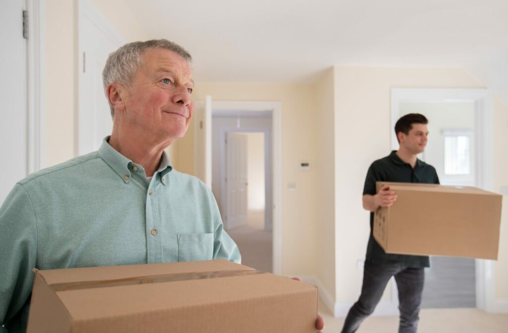 Older man and younger man carrying moving boxes into a new home.