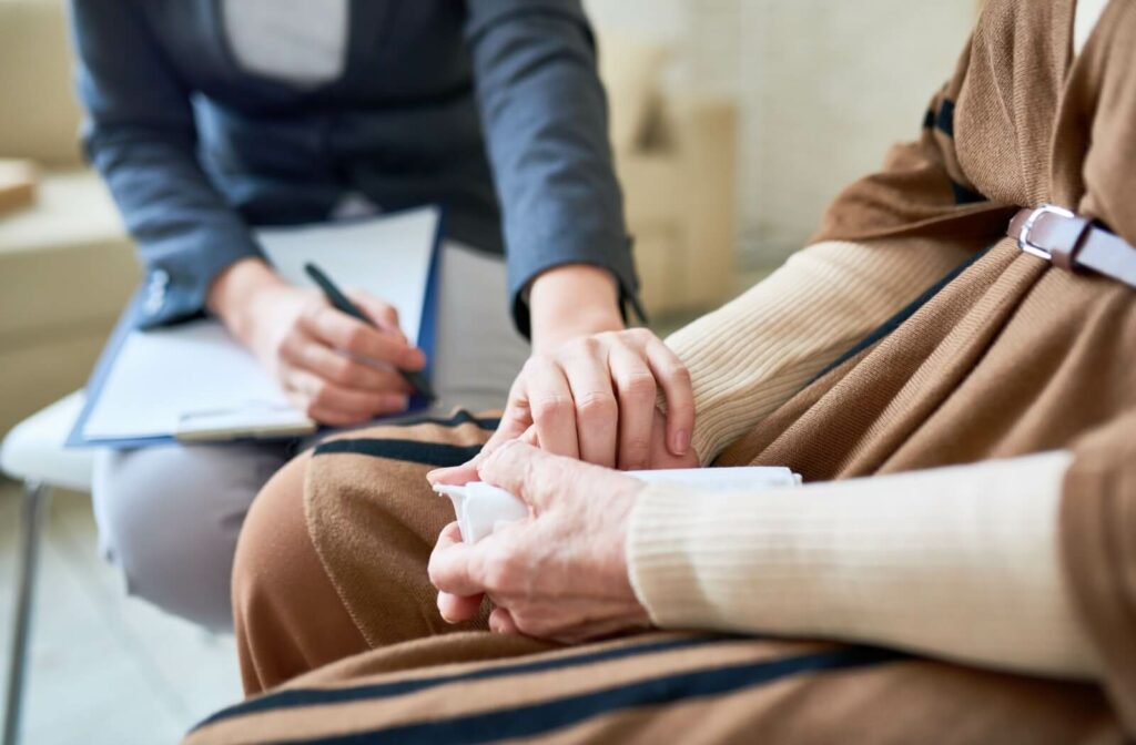 A counsellor reaches out to grab a senior’s hand to provide emotional support during a session to support their mental health
