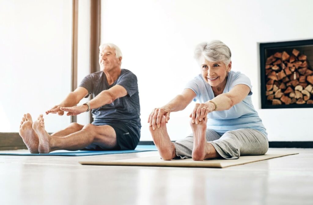 Two seniors stretching together during a workout class at an assisted living community, staying active and healthy.