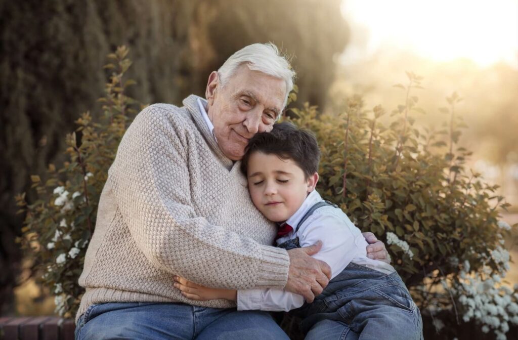 A senior hugs their young grandchild goodbye at the end of a day of visiting in their senior living home