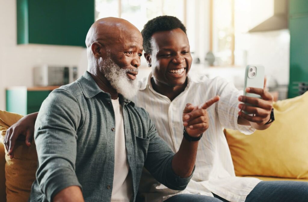An adult helps their senior parent with dementia figure out how to use a video calling app to stay better connected to family