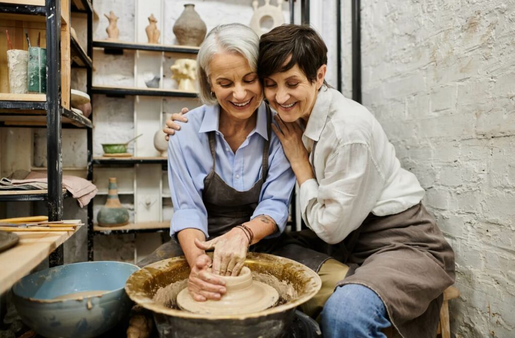 Older adults smiling while shaping clay on a pottery wheel in a creative memory care activity