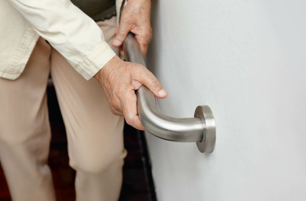 A senior holds onto a handrail for support.