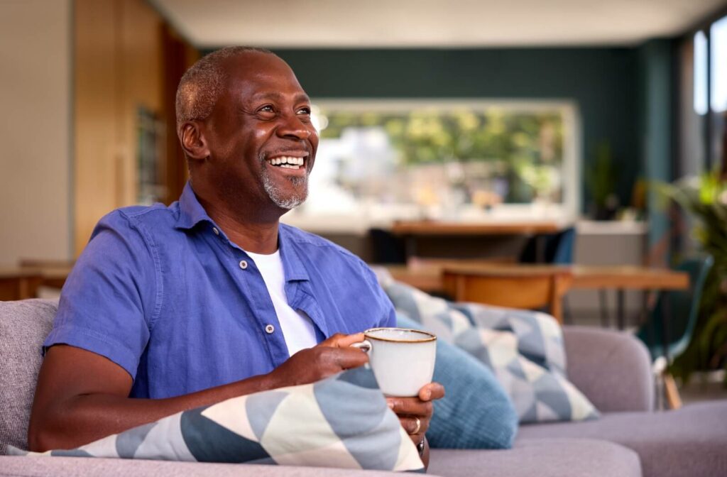 A senior sitting on a sofa drinking tea and relaxing after completing daily tasks easily