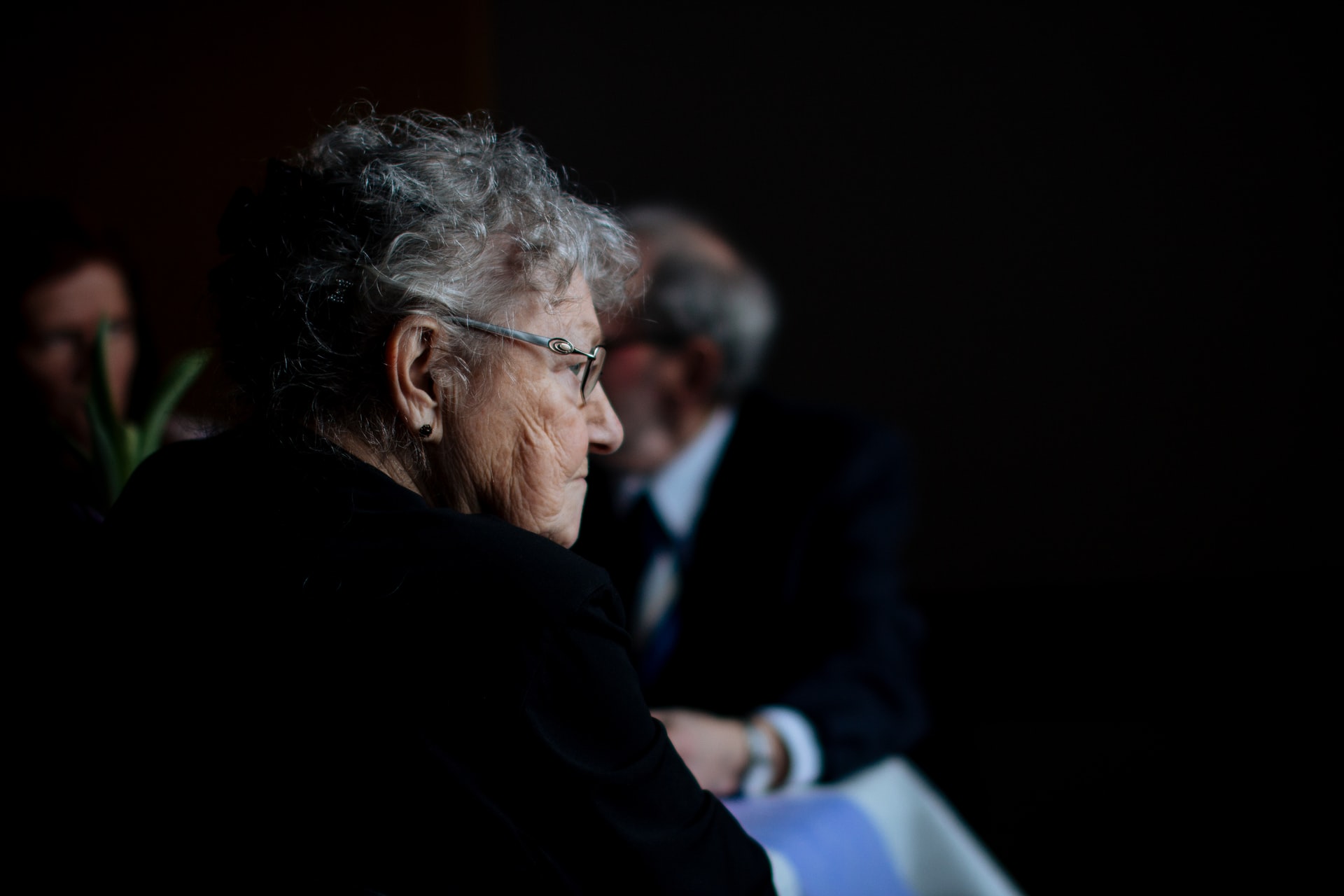 a senior woman with glasses sitting and thinking
