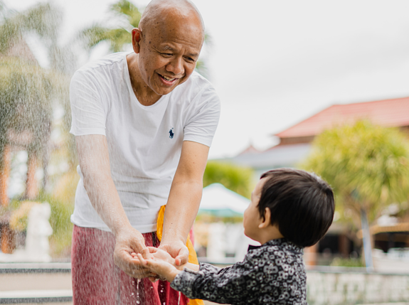 a senior man holding hands of a toddler