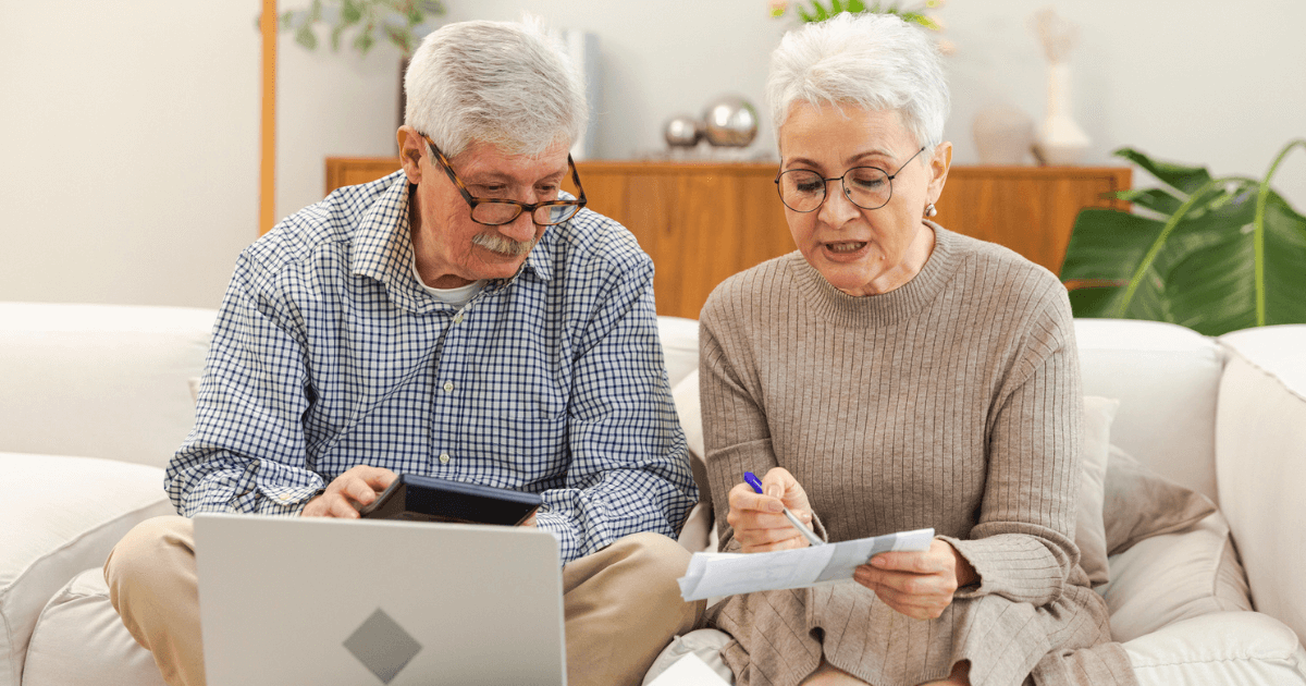 Senior couple on sofa looking for ways of funding senior living expenses.