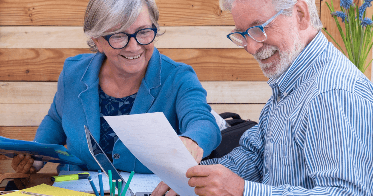 Senior couple sitting at table reviewing the cost of long-term care.