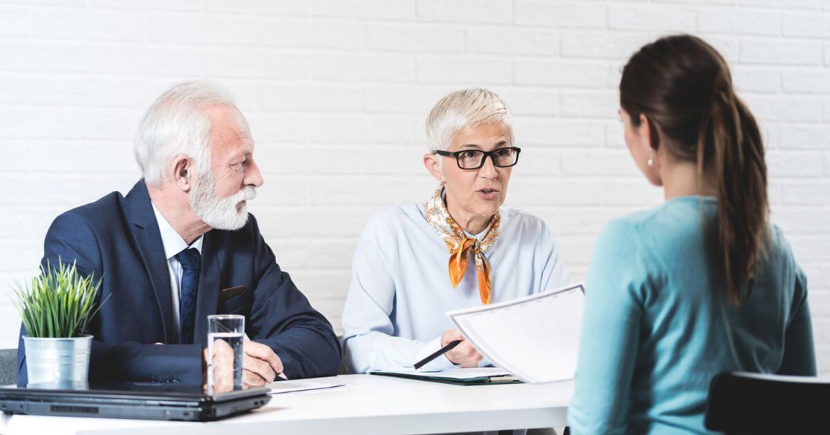 Elder couple meeting with adult woman over a Bridge Loan for a senior living community.