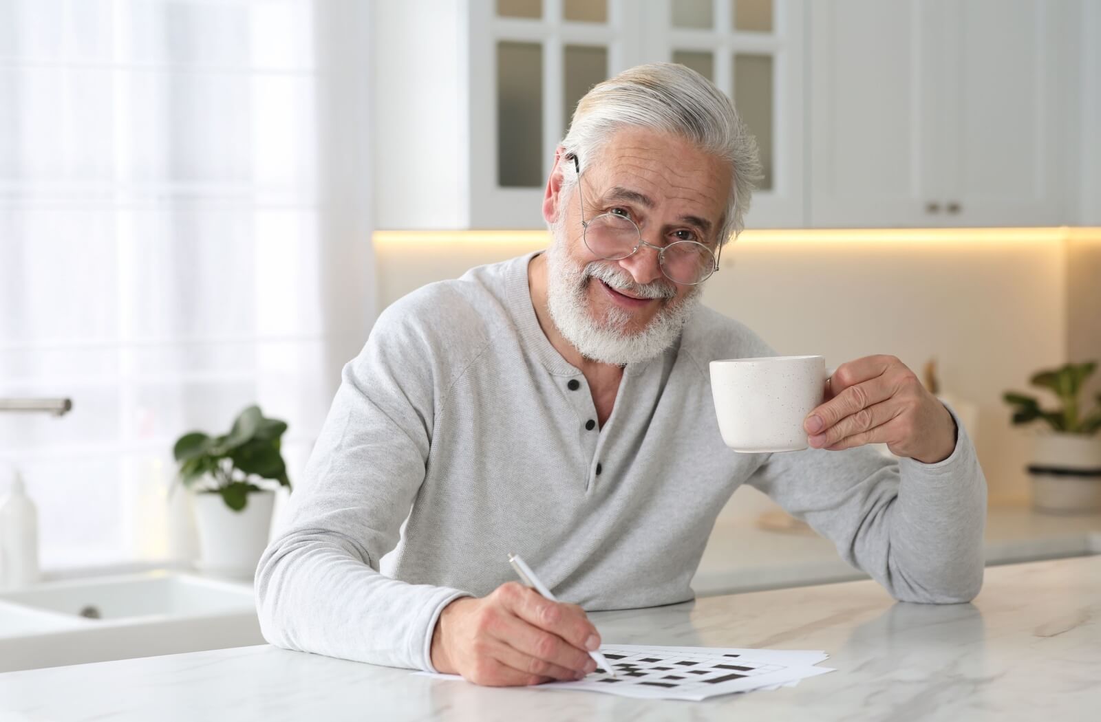 An older adult completing a morning crossword puzzle while enjoying a cup of coffee.