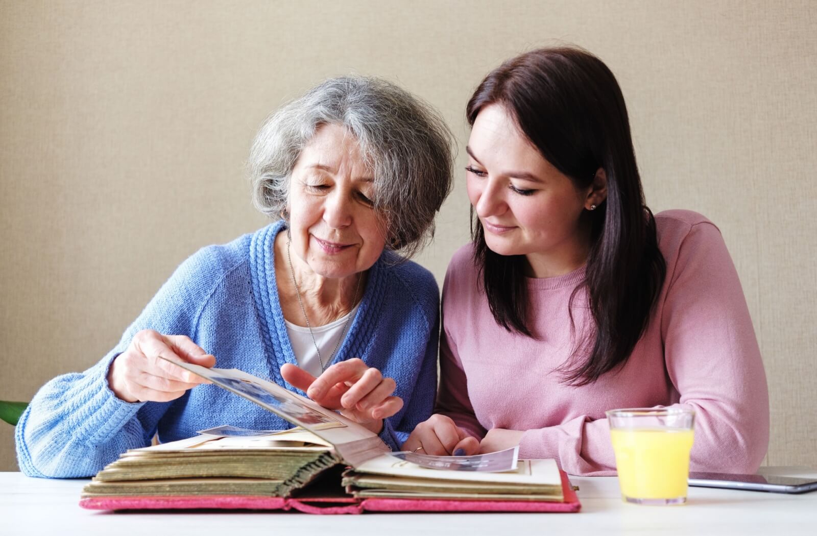 Woman and senior in memory care looking at a photo album, engaging in a memory-boosting activity.