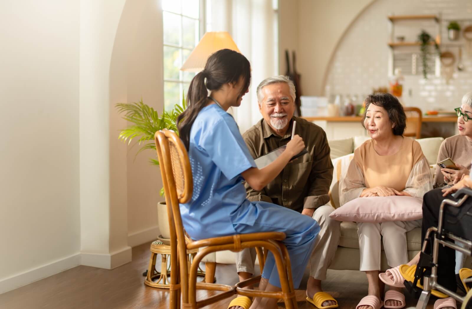 Seniors gathered together on a couch, attentively talking to a staff member taking notes.
