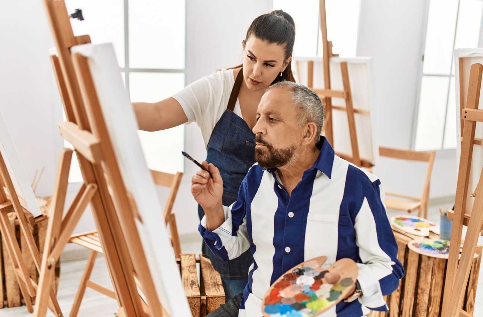 Older adults smiling while shaping clay on a pottery wheel in a creative memory care activity