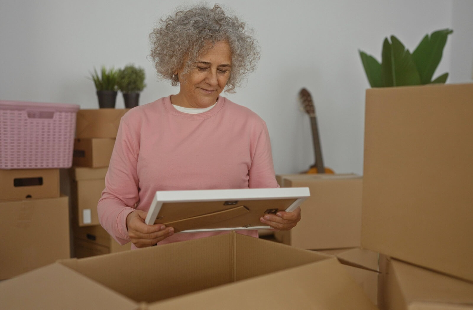 Senior woman labeling a cardboard box with marker while preparing for assisted living move