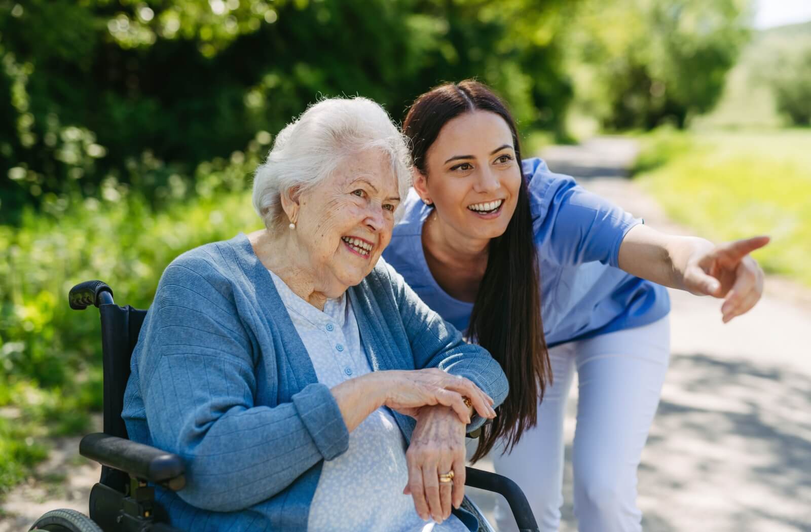 a caregiver pointing out something to senior with wheelchair in assisted living